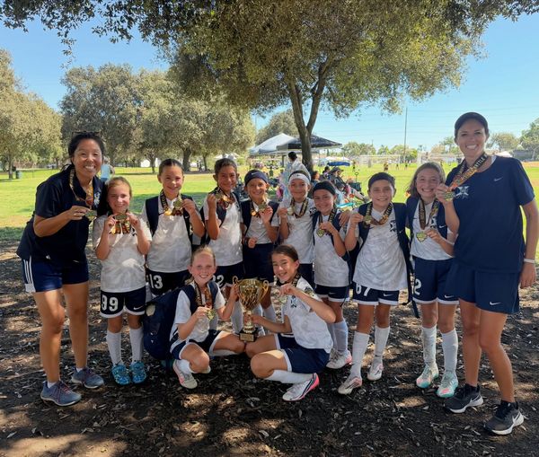 AYSO Region 84 Extra Play girls team in front of the goal with their champions banner